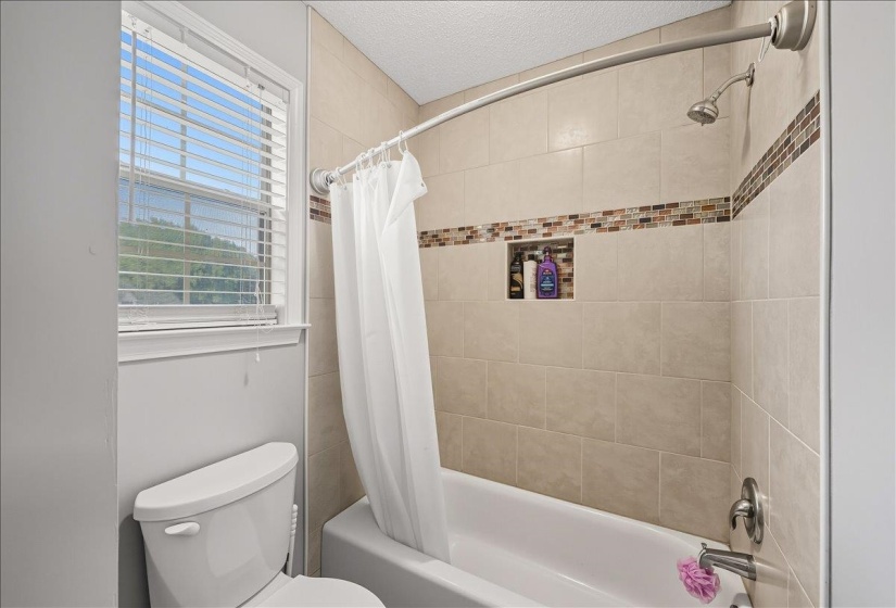 Bathroom with shower / bath combination with curtain and a textured ceiling