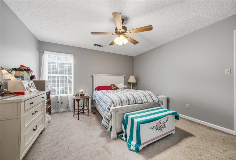 Bedroom with a textured ceiling, a ceiling fan, and light carpet