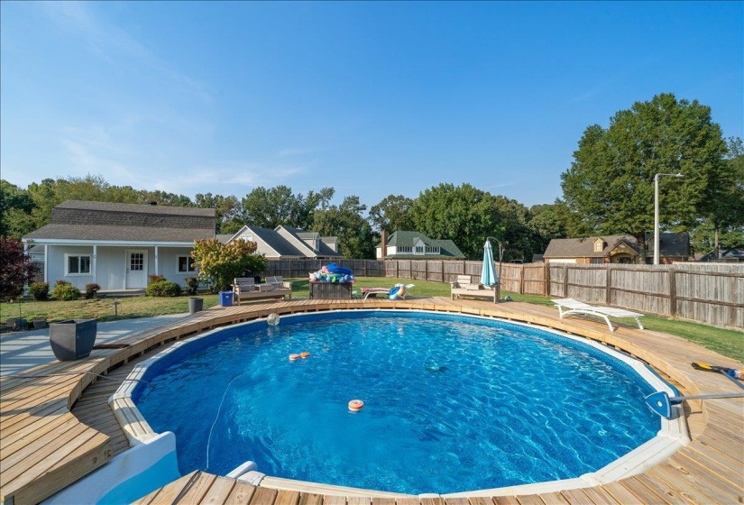View of pool featuring a fenced backyard, an outbuilding, patio surround, and a wooden deck