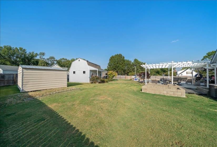 Fenced backyard featuring a pergola, a patio area, and an outdoor structure
