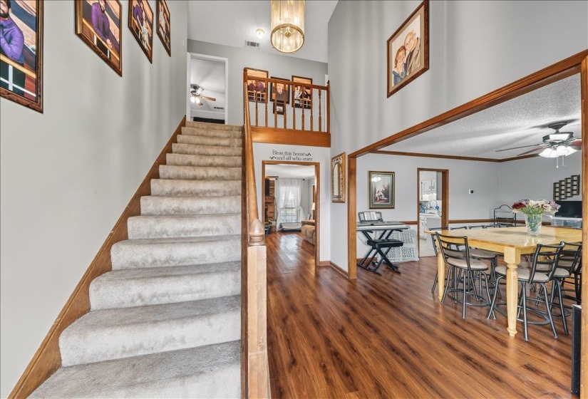 Stairway featuring a ceiling fan, wood finished floors, a high ceiling, and a chandelier