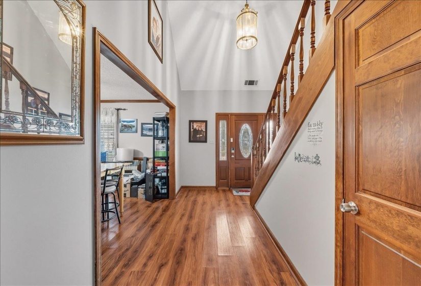 Foyer entrance with wood finished floors, a high ceiling, and hanging lights