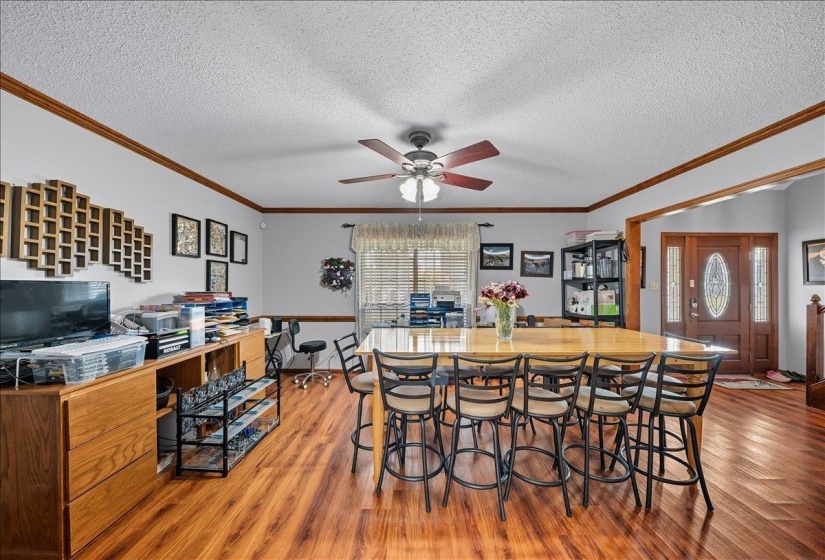 Dining space with light wood-style flooring, crown molding, ceiling fan, and a textured ceiling