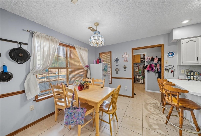 Dining room with a textured ceiling, light tile patterned floors, and hanging lights
