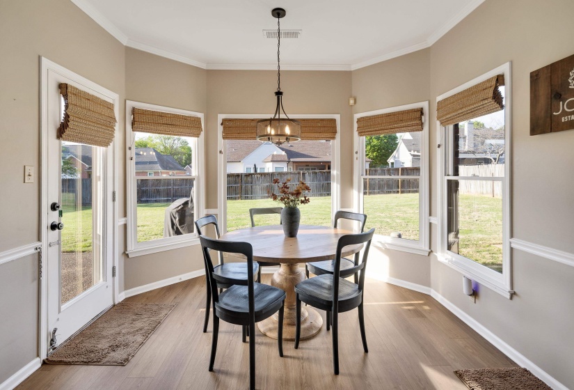 Dining space with plenty of natural light, wood finished floors, ornamental molding, and hanging lights