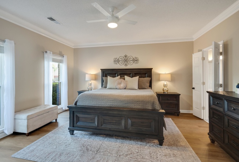 Bedroom featuring ornamental molding, light wood-style flooring, and a ceiling fan
