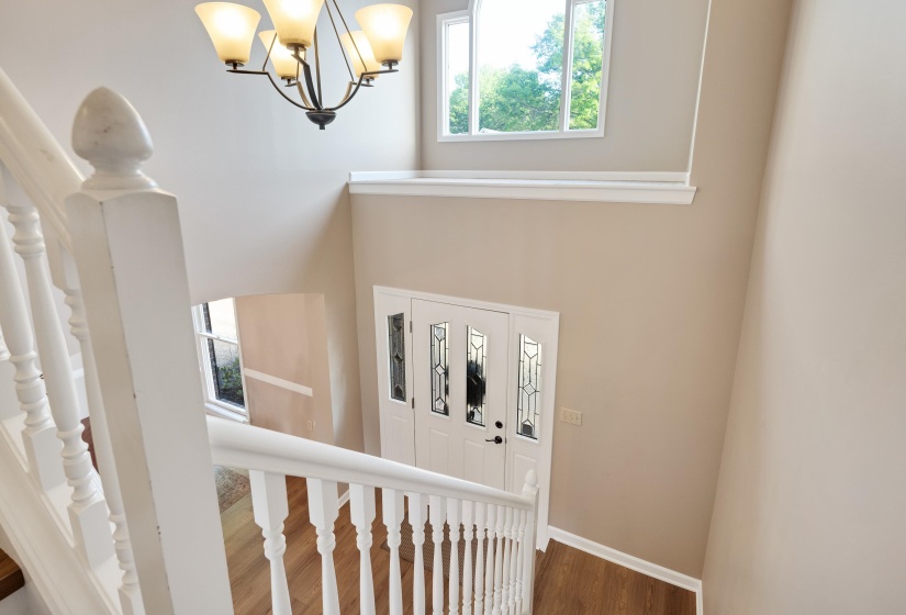 Staircase with plenty of natural light, a chandelier, and wood finished floors