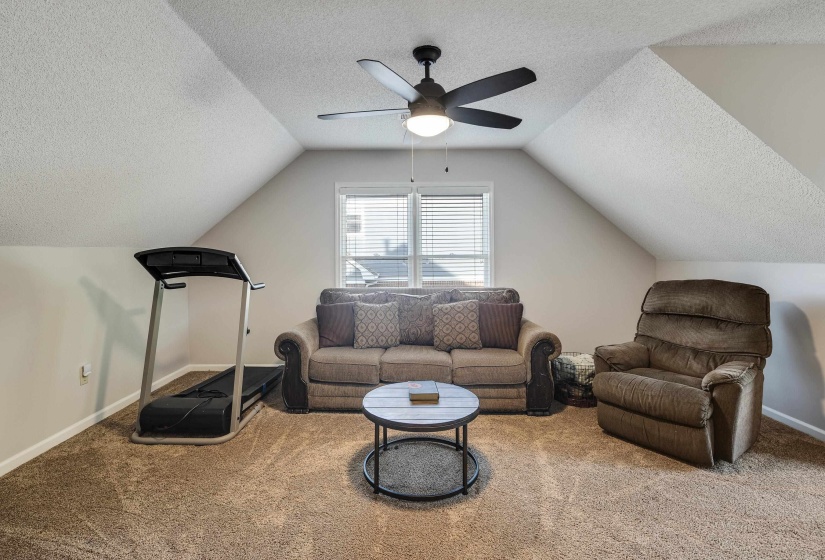 Living area with a textured ceiling, carpet floors, and ceiling fan