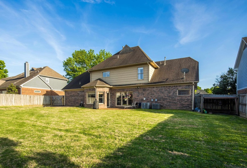 Rear view of property featuring brick siding, a fenced backyard, a gate, and a patio area