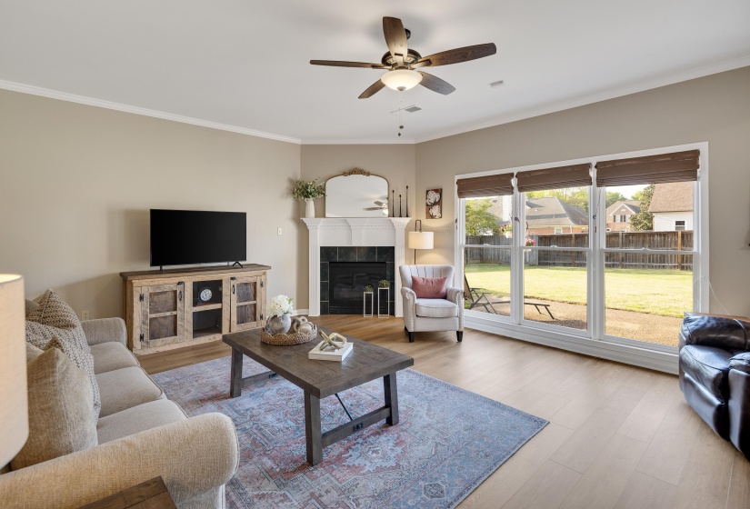 Living room featuring ornamental molding, a tile fireplace, ceiling fan, and wood finished floors