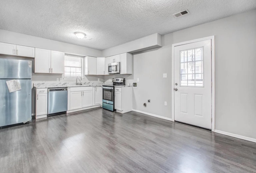 Kitchen featuring stainless steel appliances, a textured ceiling, white cabinets, and dark wood-type flooring
