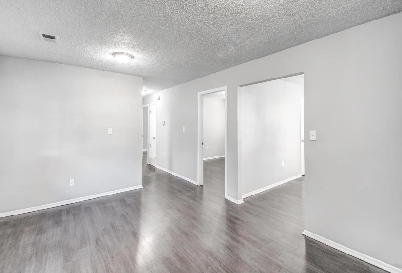 Empty room with a textured ceiling and dark wood-style flooring