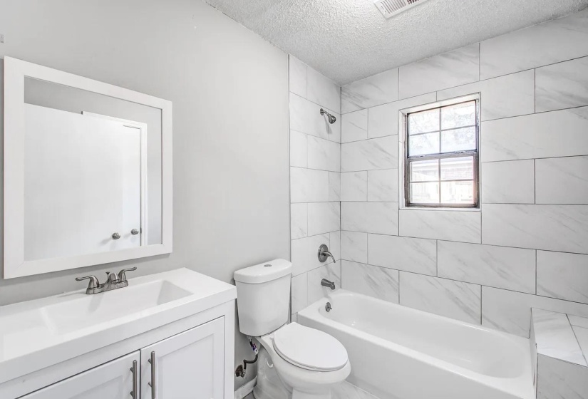 Full bath with vanity, tub / shower combination, and a textured ceiling