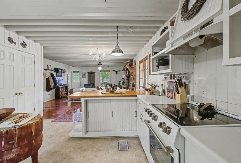 Kitchen with a peninsula, white electric stove, a ceiling fan, pendant lighting, and open floor plan