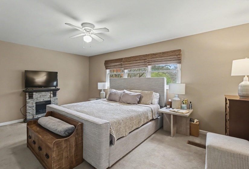 Carpeted bedroom with a fireplace and a ceiling fan
