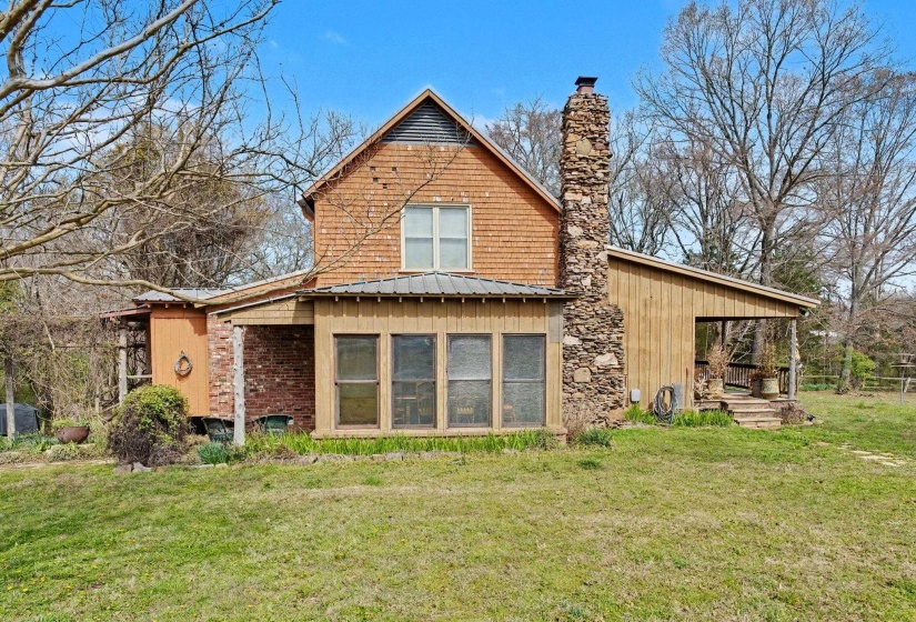 Back of property featuring a metal roof, a lawn, and a chimney