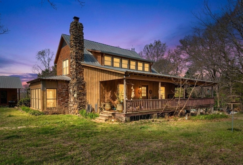 Back of house at dusk with a porch, a yard, board and batten siding, and a metal roof