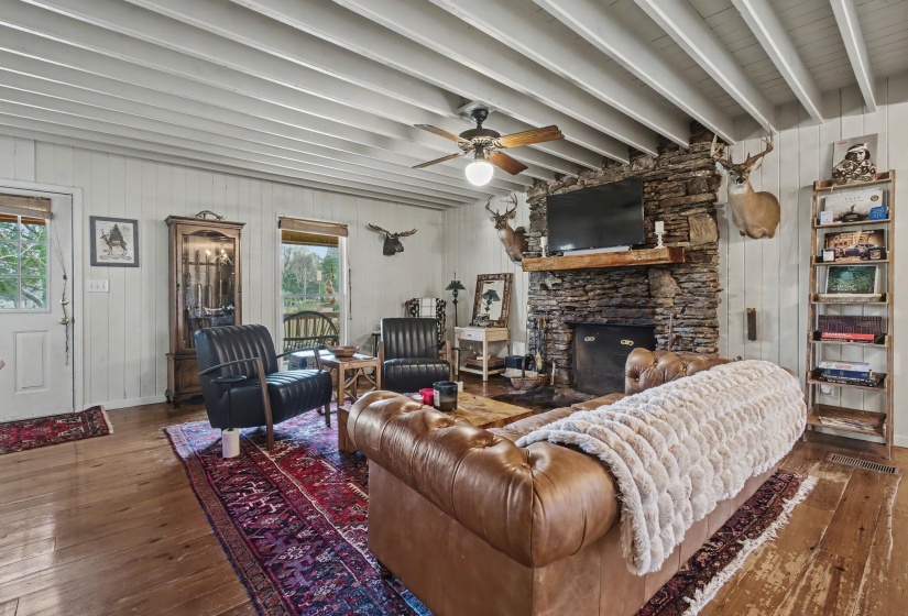 Living room with healthy amount of natural light, a ceiling fan, wood walls, and hardwood / wood-style floors