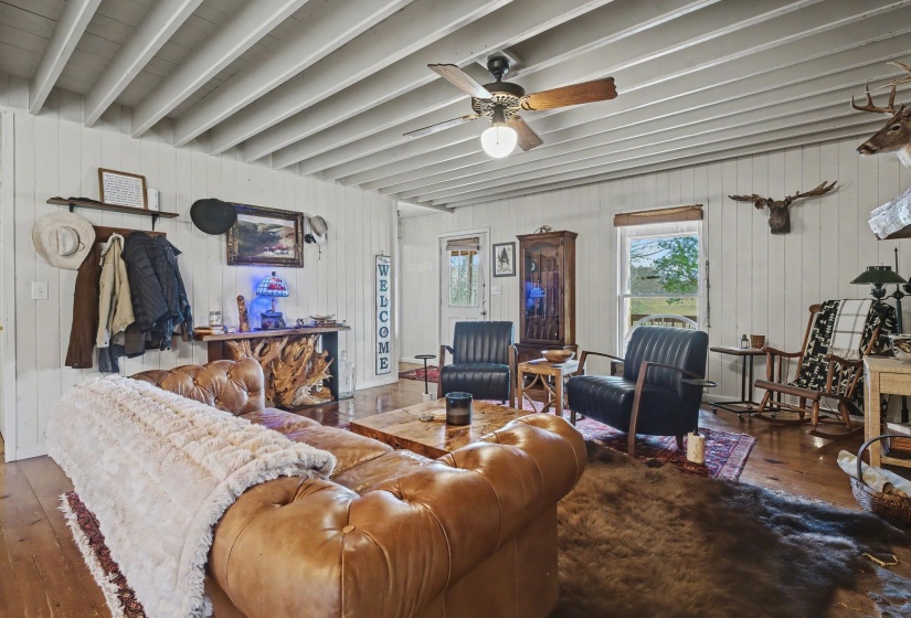 Living area featuring hardwood / wood-style flooring, a ceiling fan, and wood walls