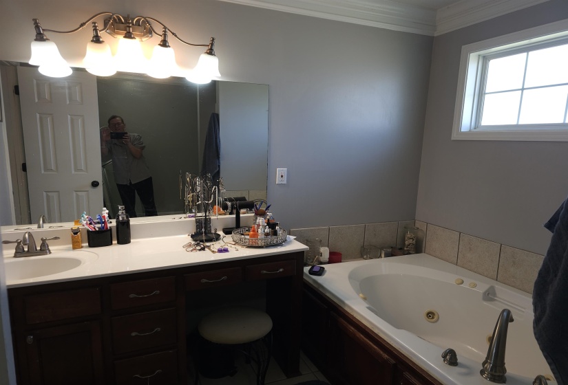 Full bath featuring vanity, crown molding, and a whirlpool tub