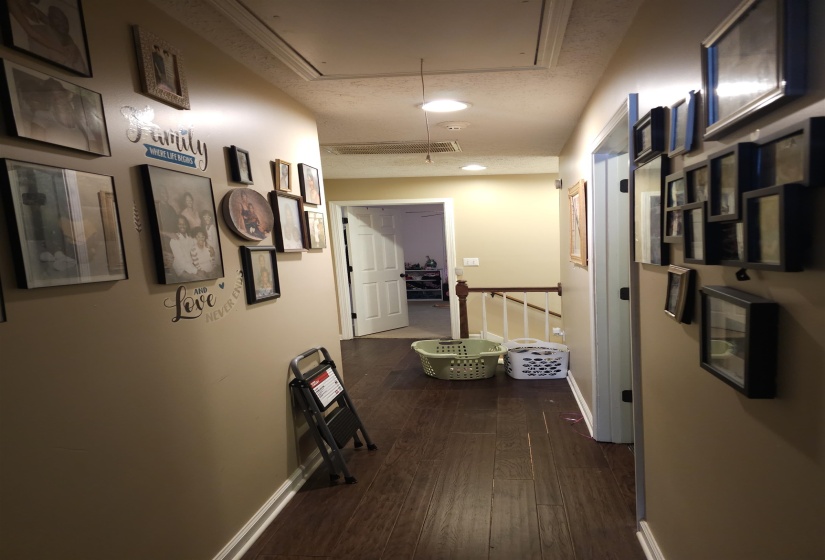 Corridor featuring an upstairs landing and dark wood finished floors