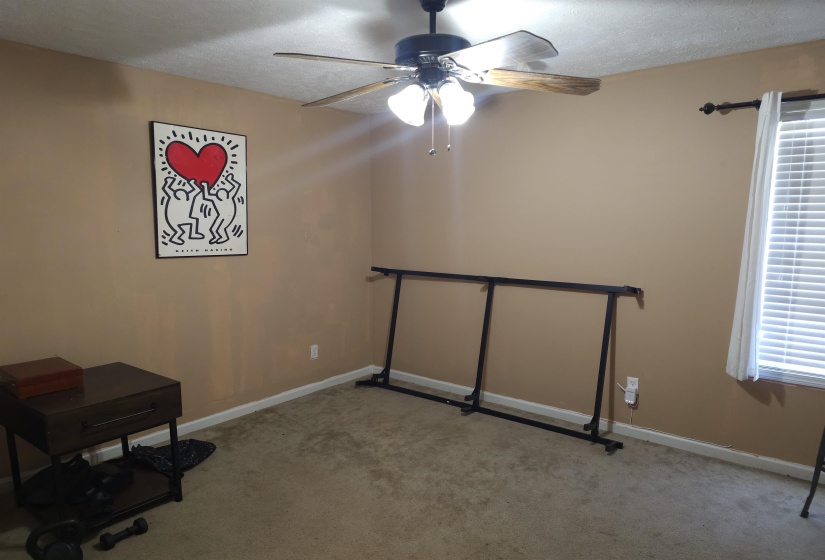Unfurnished office with ceiling fan, light carpet, and a textured ceiling