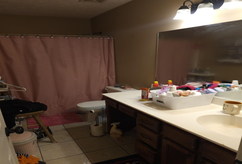 Bathroom with vanity, curtained shower, light tile patterned flooring, and a textured ceiling