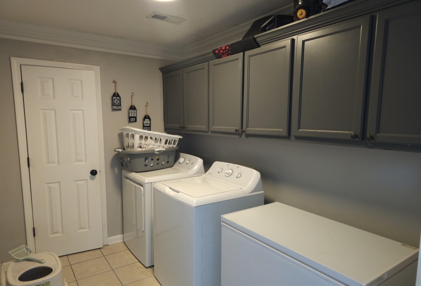 Laundry room featuring cabinet space, ornamental molding, light tile patterned floors, and separate washer and dryer
