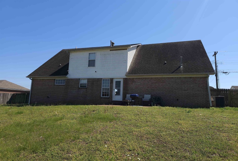 Rear view of property featuring brick siding, a patio, and a shingled roof