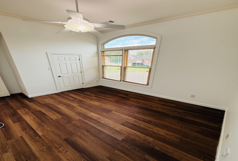 Unfurnished bedroom with dark wood-style floors, ceiling fan, and crown molding