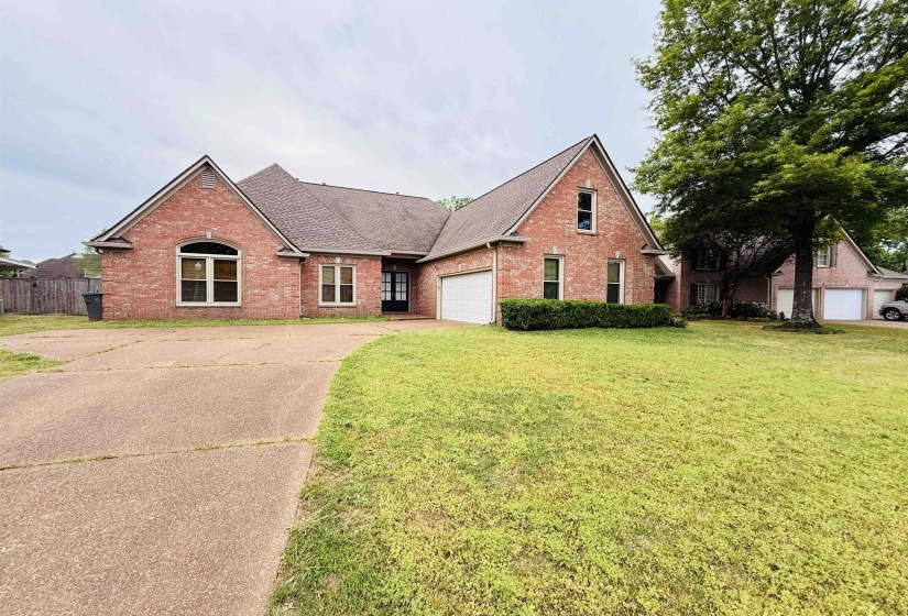 View of front of home with brick siding, roof with shingles, concrete driveway, and a front lawn