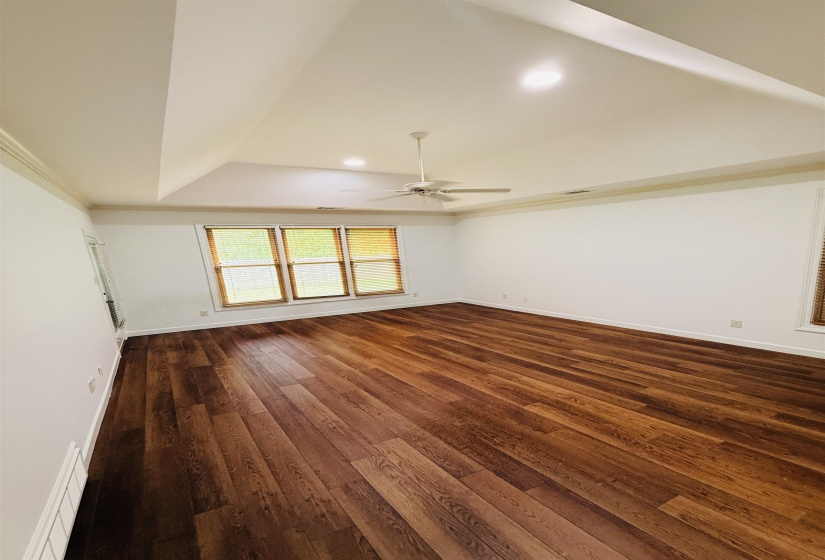 Spare room with a tray ceiling, dark wood finished floors, recessed lighting, a ceiling fan, and ornamental molding
