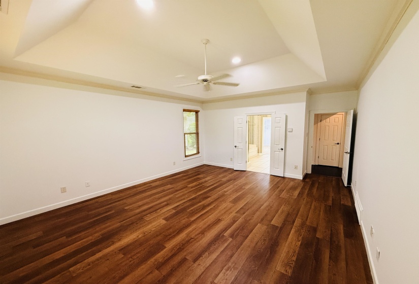 Unfurnished bedroom with dark wood finished floors, ceiling fan, crown molding, and a tray ceiling