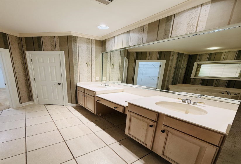 Full bathroom featuring double vanity, light tile patterned floors, a garden tub, ornamental molding, and recessed lighting