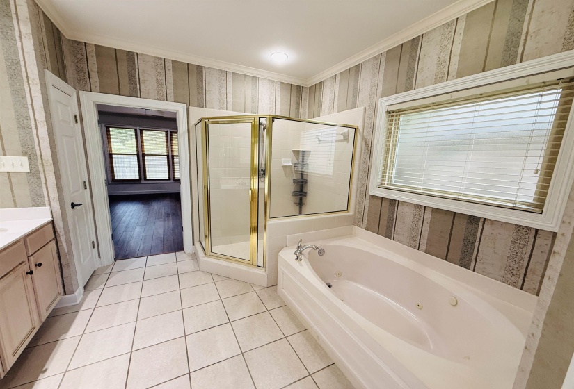 Full bathroom with wallpapered walls, a stall shower, vanity, a tub with jets, and light tile patterned flooring
