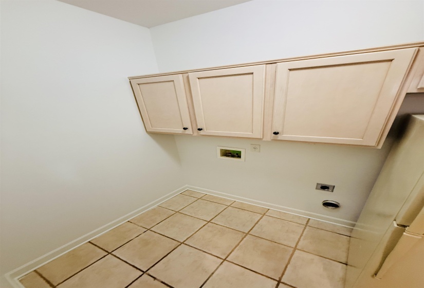 Laundry room with light tile patterned flooring, hookup for an electric dryer, cabinet space, and washer hookup