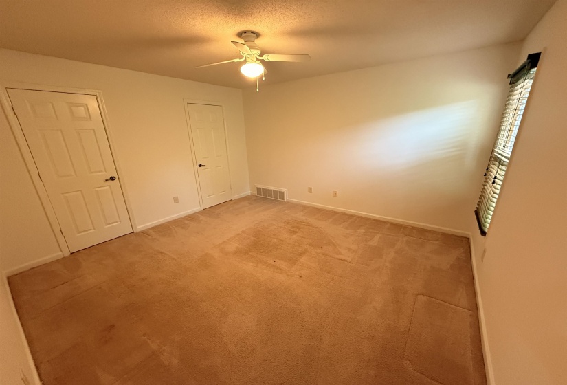 Unfurnished bedroom featuring light carpet, ceiling fan, and a textured ceiling