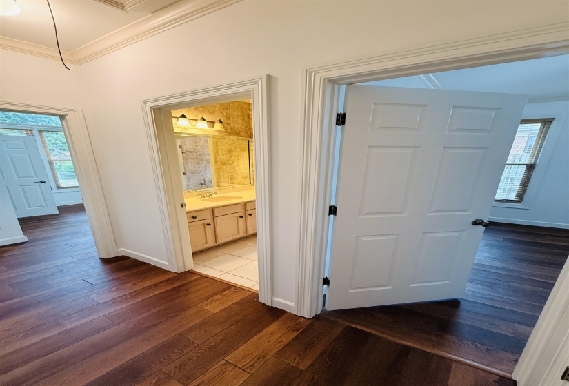 Corridor with healthy amount of natural light, dark wood-type flooring, and ornamental molding