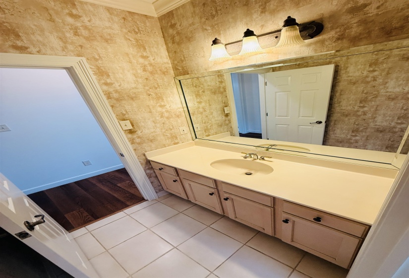 Bathroom with vanity, light tile patterned flooring, and crown molding