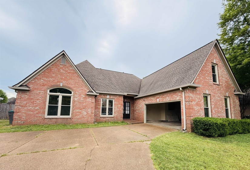 Traditional-style home with roof with shingles, brick siding, an attached garage, driveway, and a front lawn