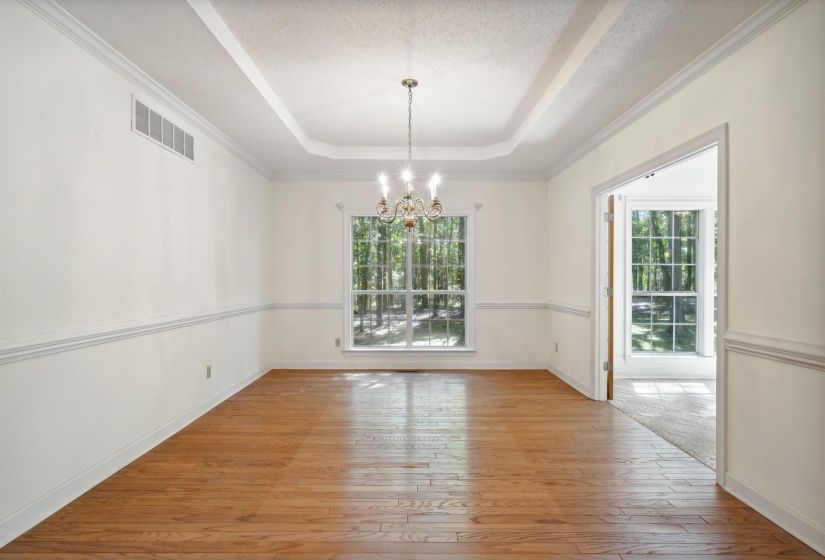 Unfurnished dining area featuring hanging lights, a raised ceiling, light wood-style flooring, healthy amount of natural light, and a textured ceiling