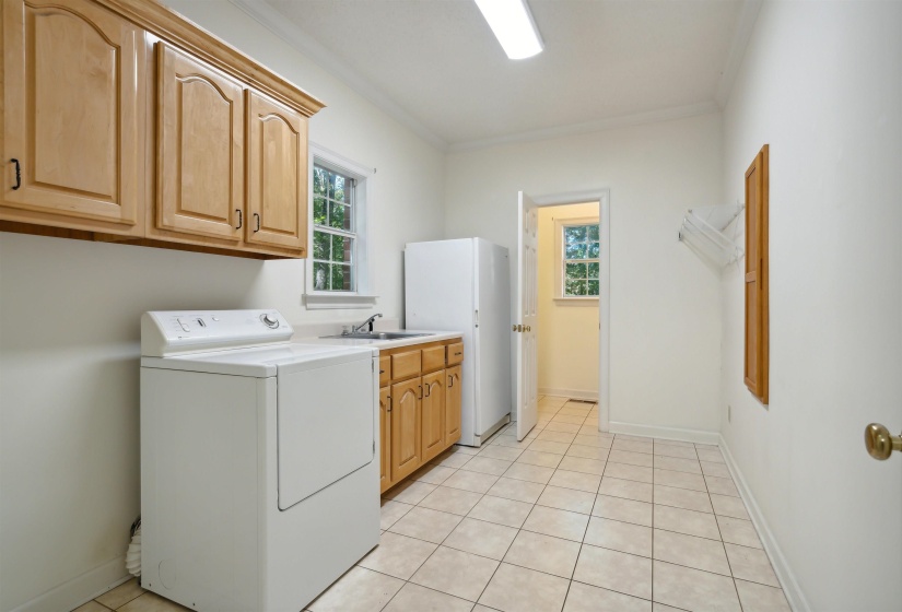 Laundry area featuring washer / clothes dryer, cabinet space, ornamental molding, and light tile patterned flooring