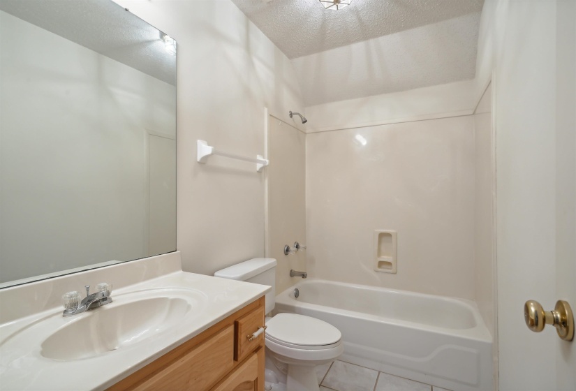 Bathroom featuring vanity, shower / bath combination, a textured ceiling, and light tile patterned floors