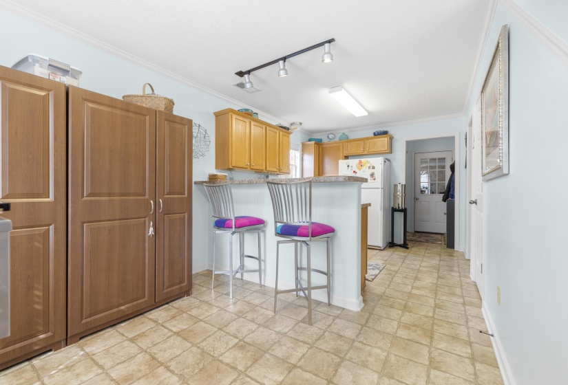 Kitchen featuring crown molding, a kitchen breakfast bar, track lighting, freestanding refrigerator, and a peninsula