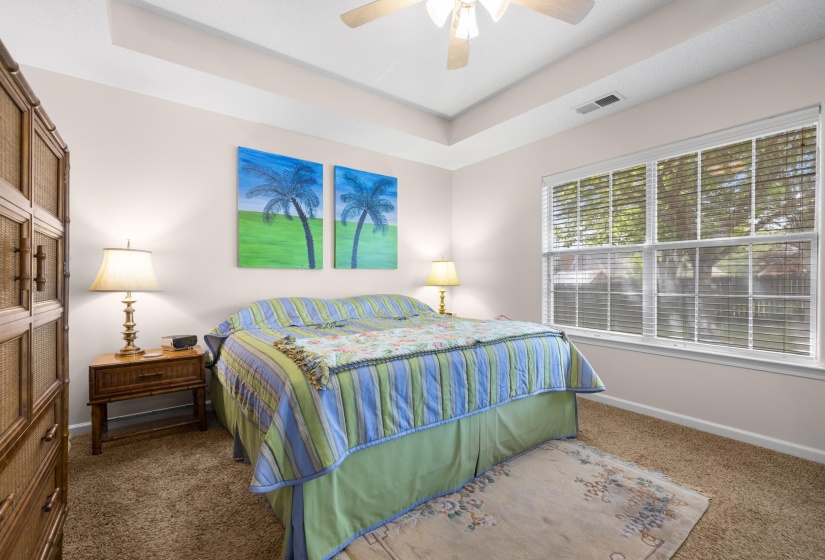Bedroom featuring carpet floors, a tray ceiling, and ceiling fan
