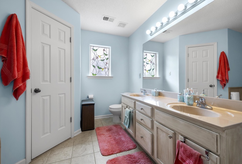 Bathroom featuring double vanity, light tile patterned floors, and a textured ceiling