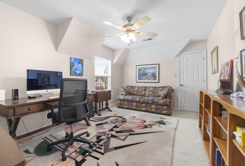 Home office featuring a ceiling fan, light colored carpet, and a textured ceiling
