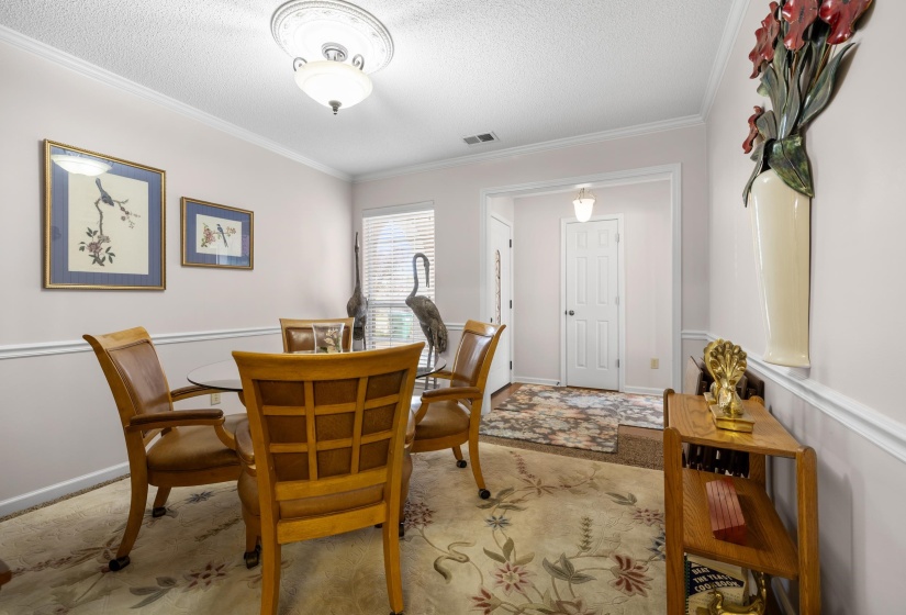 Dining space featuring a textured ceiling and ornamental molding