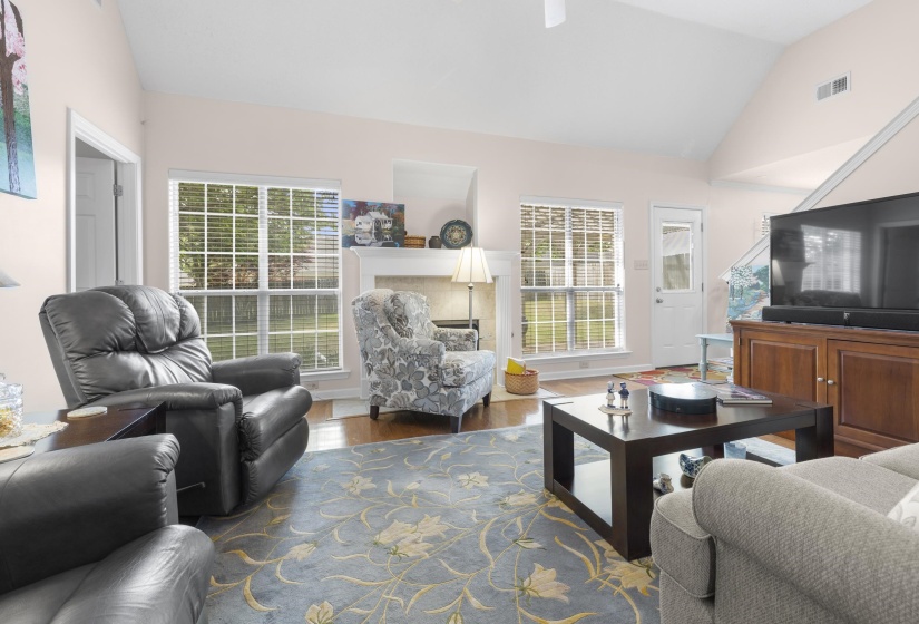 Living area with lofted ceiling, wood finished floors, plenty of natural light, and a ceiling fan