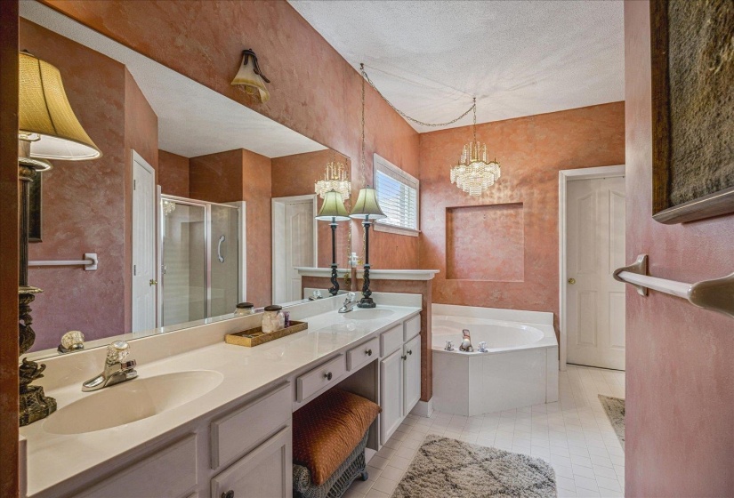 Bathroom with a shower stall, double vanity, a textured ceiling, a garden tub, and a chandelier